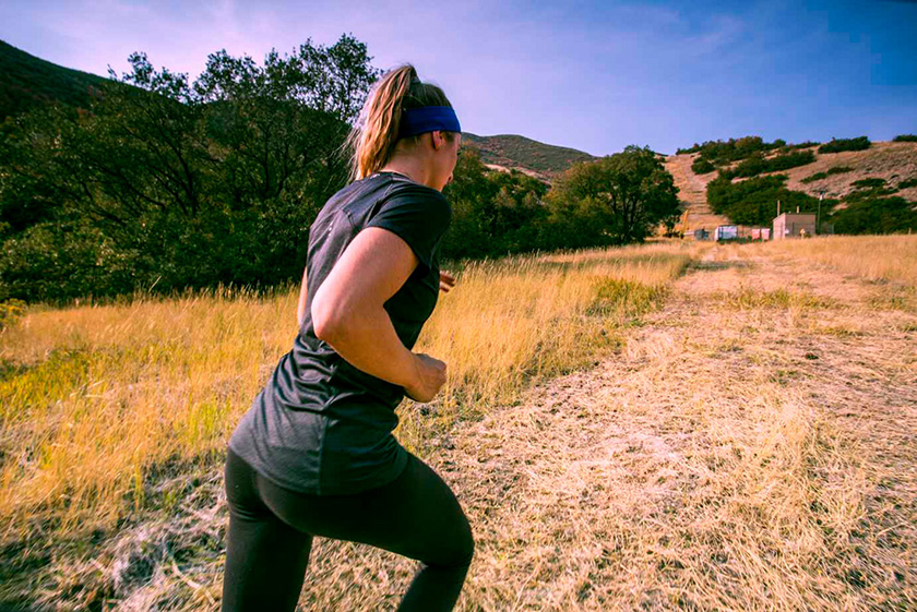 Mergina sportiniais antblauzdžiais ir marškinėliais bėgioja kalnų taku Moteris bėgioja kaimo keliuku