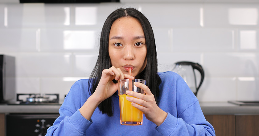 Девушка азиатской внешности пьет сок