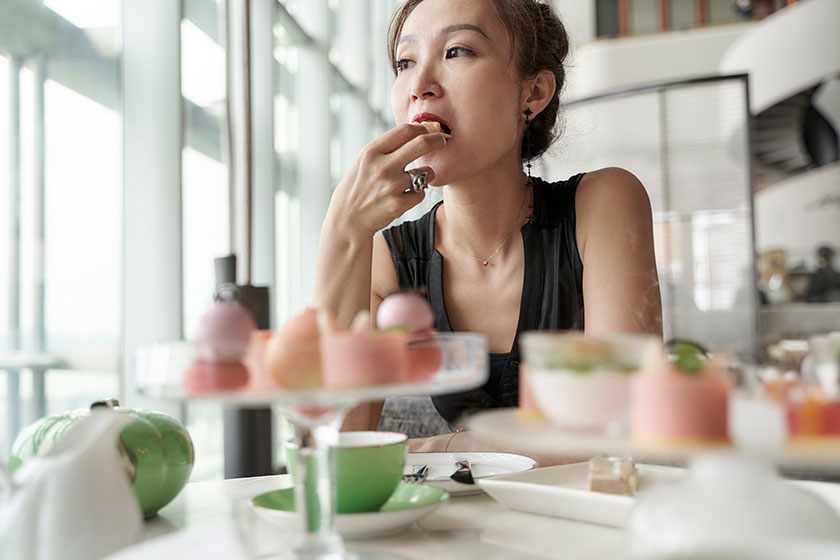 Женщина сидит за столом с десертами